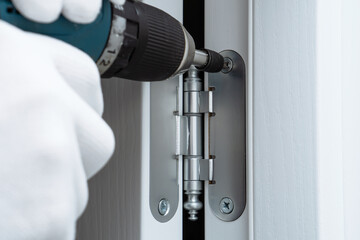 Man hands installing interior door and screwing door hinge with screwdriver, close up