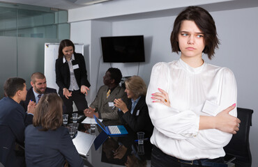 Business team discussing in meeting room with upset young woman foreground