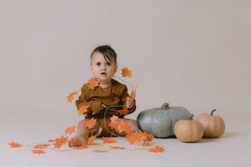 Cute small baby is staying near a pumpkins. Studio photography.