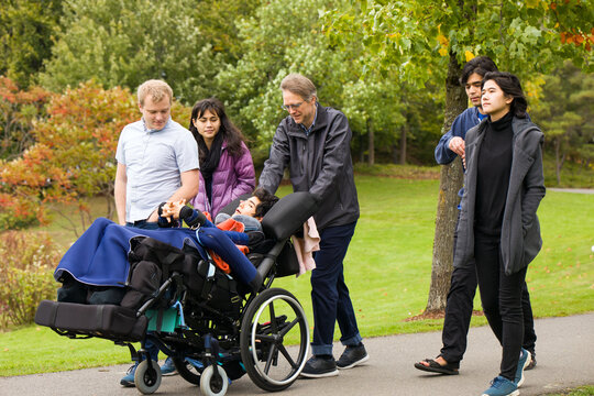 Multiracial group walking at park with child in wheelchair