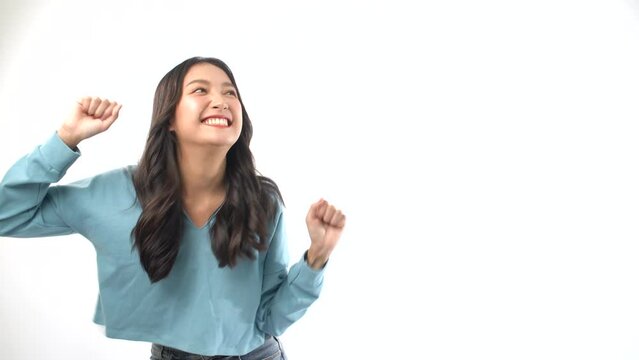 Excited Asian woman surprised wow sale product looking at empty over white background. Advertisement positive cheerful young girl presenting to copy space shocked amazed happy dance over isolated.
