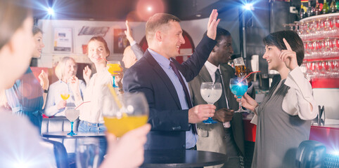 Cheerful businessman with female colleague dancing and drinking alcohol, having fun at office party...