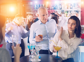 Disgruntled young woman gesturing stop to male colleague flirting with her during firms party