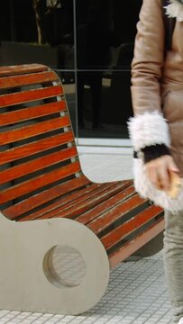 mujer sentada en un banco con el telefono en la mano	