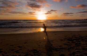 hombre joven ejercitandose o haciendo running en la playa en la puesta de sol o el amanecer