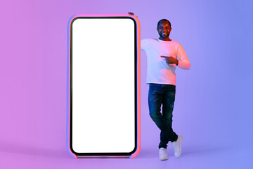 Positive black man pointing at big cell phone, mockup