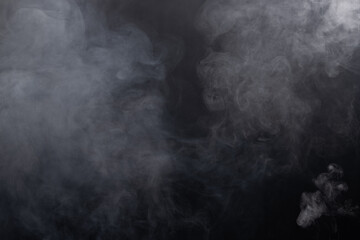 Dense Fluffy Puffs of White Smoke and Fog on black Background, Abstract Smoke Clouds, Movement Blurred out of focus. Smoking blows from machine dry ice fly fluttering in Air, effect texture