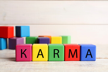 Word Karma made of colorful cubes with letters on white wooden table