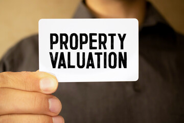 Business concept. On a brown surface is a house, a pen and a notepad with the inscription - Property Value