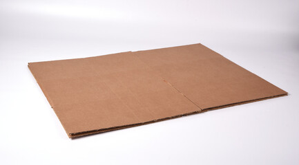 A brown cardboard box disassembled on a white background lies on a sheet