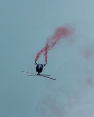 inverted helicopter at an airshow with smoke