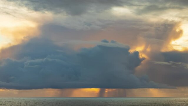 Storm clouds and rain in the distance as the sun sets causing yellow sky - timelapse