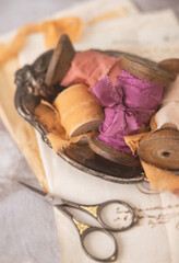 Wooden Spools of Colorful Silk Ribbon in a Silver Bowl on Antique French Papers