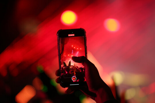 fan taking photo with cell phone at a concert close up
