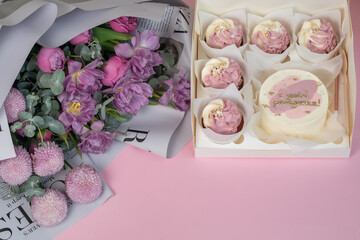 A beautiful bouquet and cupcakes lie on the pink table