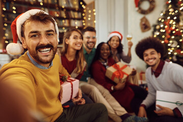 Happy man taking selfie with his friends on Christmas day at home.