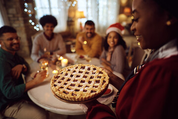 Close up of black woman serving sweet pie during Christmas lunch at home. - obrazy, fototapety, plakaty
