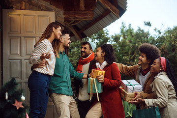Happy couple welcoming their friends on the doorstep on Christmas day.
