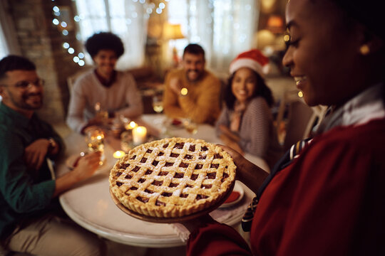 Close up of black woman serving sweet pie during Christmas lunch at home.