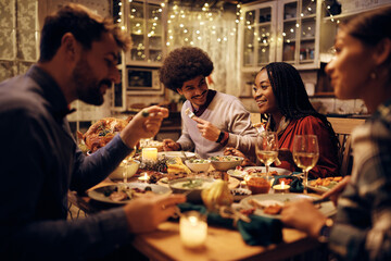 Happy black woman enjoys in Thanksgiving dinner with friends in dining room.