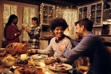 Young happy men talk at dining table during Thanksgiving dinner.
