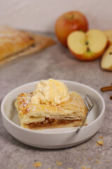 piece of an apple strudel roll with cinnamon and ice cream on top