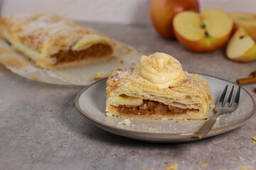 piece of an apple strudel roll with cinnamon and ice cream on top
