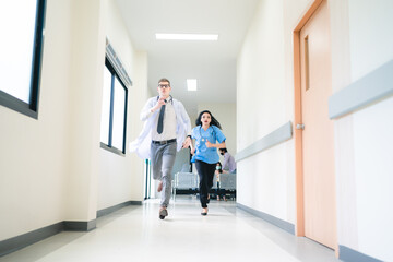 Young male and female professional doctor and surgeon holding clipboard with stethoscope and wearing lab coat and uniform running in hospital hallway and corridor during an emergency