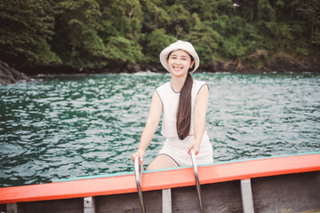 woman relaxing outdoors On a small boat in the middle of the sea.Beautiful mature woman enjoys summer sea trip, female on side of small boat. Phuket Sea Thailand