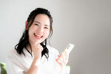 スマホを素敵な笑顔で持つカメラ目線のかわいい女性