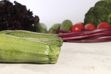 Par de calabazas frente a un fondo creado de diferentes verduras