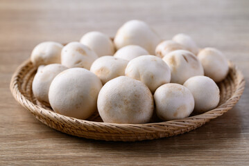 Fresh white champignon mushroom in basket on wooden background