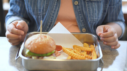 Obraz na płótnie Canvas Woman enjoy eating a hamburger and french fries