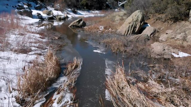 Calm and Tranquil Stream Flowing Through Rocks in Snowy Canyon • Steady Drone Video • HD Horizontal Shot