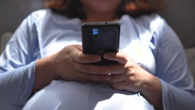 Pregnant woman using mobile phone at home