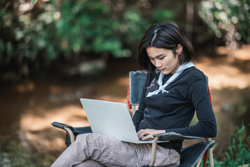 Young woman use laptop while camping in forest
