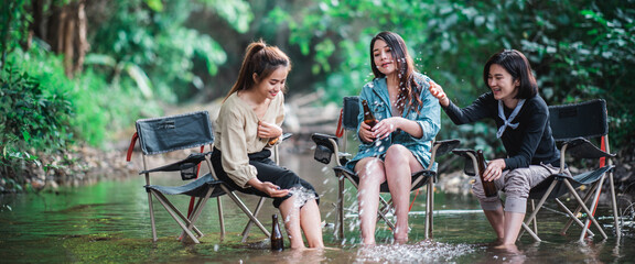 Young women sitting and drink beverage while camping in forest