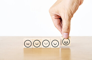 Hand of a businessman chooses a smiley face icon on wood block cube, The best excellent business services rating customer experience, Satisfaction survey concept, Service rating