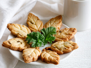 Delicious freshly baked shortbread homemade cookies with scented leaved pelargonium on a white plate with cup of tea or coffee, top view, close up, selective focus
