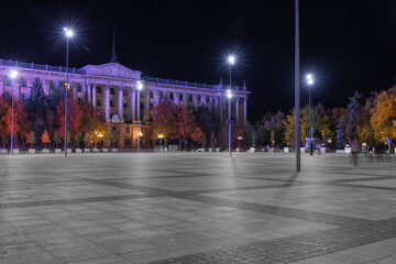 View of city square with old building and street lights at night