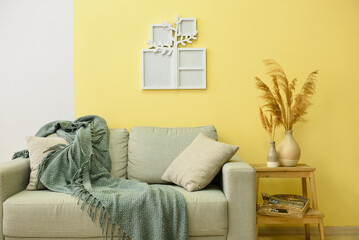Cozy interior of living room with sofa and family tree photo frame