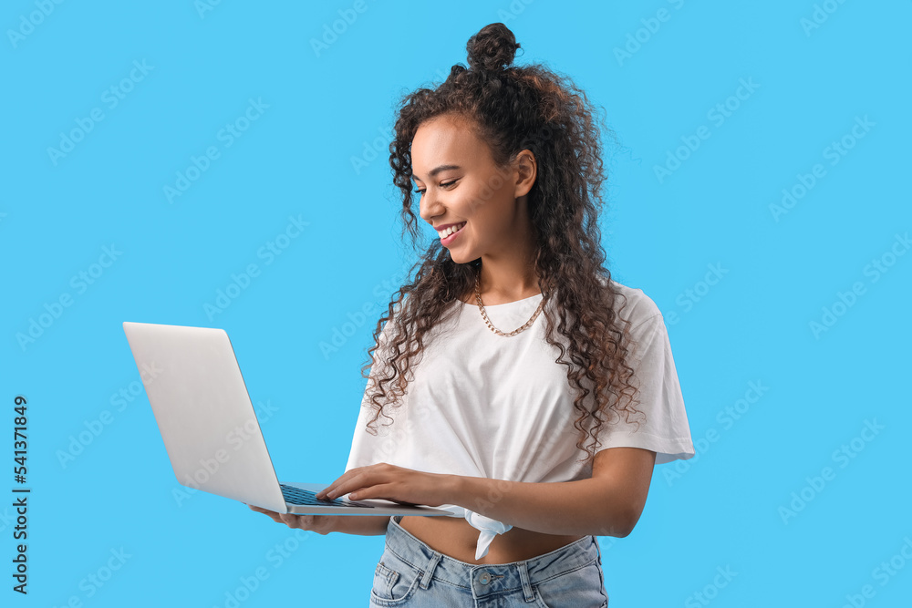 Sticker Young African-American woman using laptop on blue background