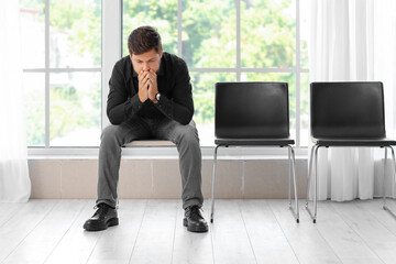 Sad fired young man sitting in office