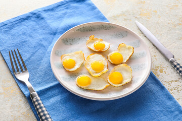 Plate with tasty fried quail eggs on light background, closeup
