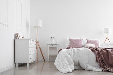 Interior of light cozy bedroom with tables and lamps