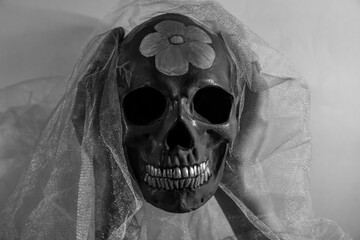 Woman with painted skull for Mexico's Day of the Dead (El Dia de Muertos) and veil on grey background