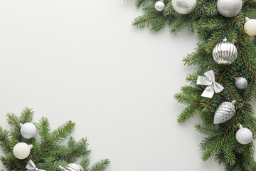 Fir tree branches with silver Christmas decorations on white background