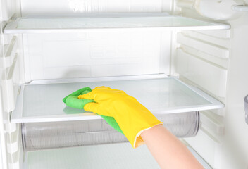 Deep Cleaning service. House cleaning. Washing fridge. Woman hand in yellow rubber protective glove...