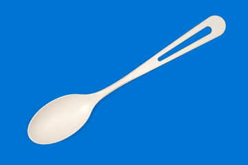 A white plastic spoon on a blue background.