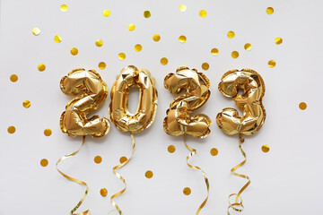 Figure 2023 made of balloons, confetti and serpentine on grey background